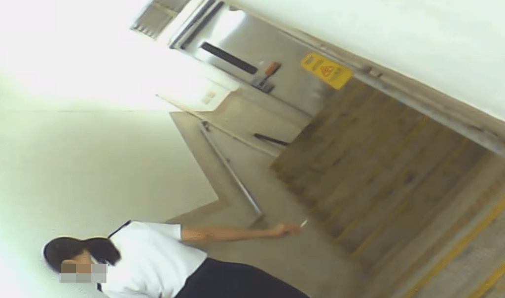 一名身穿食環署制服的女子獨自在梯間吸煙。網上片段截圖