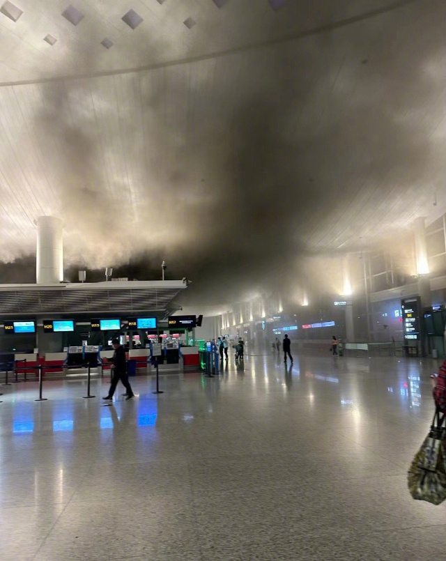 机场T3航站楼大厅内冒出浓烟，多名旅客往外撤离。 微博图
