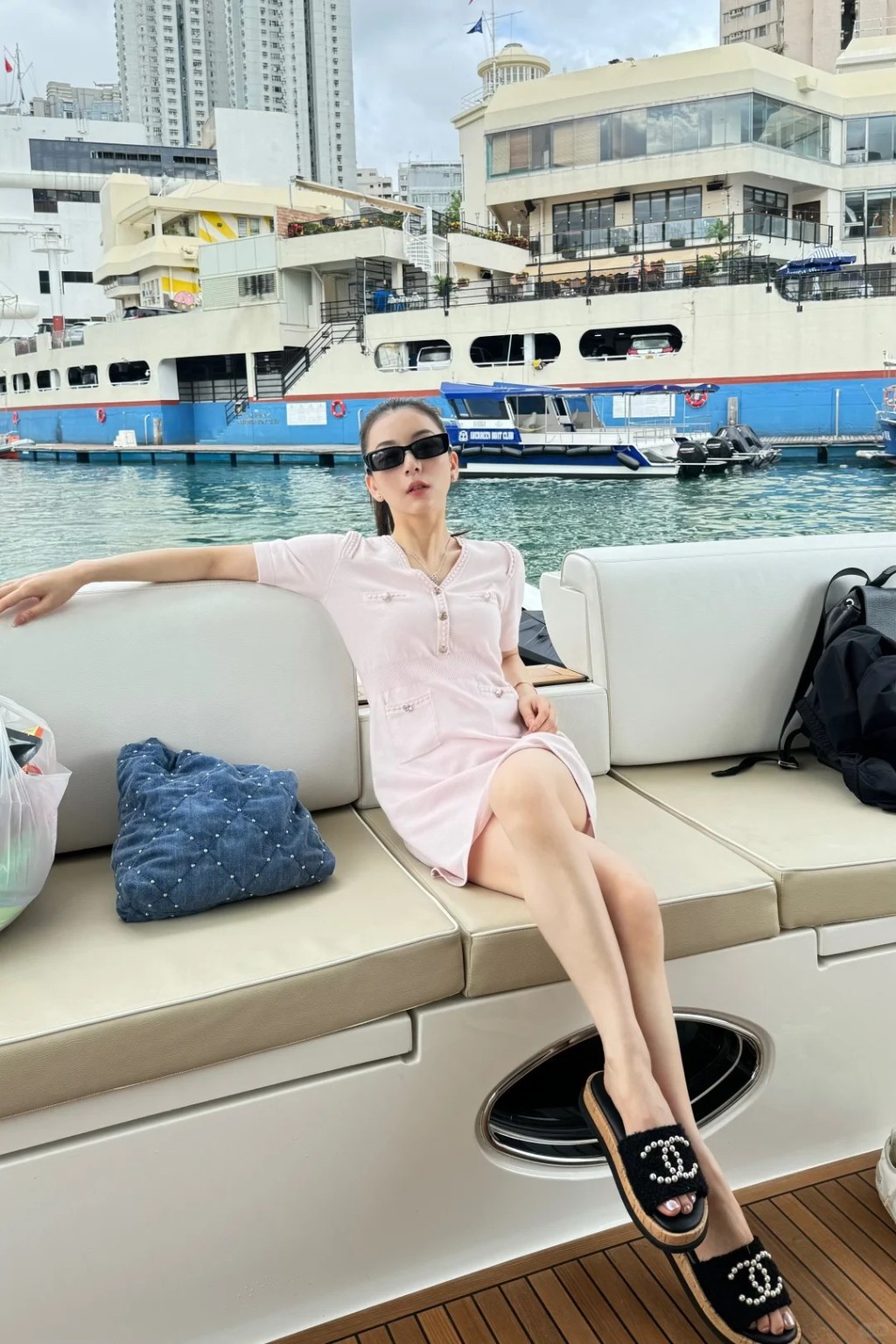 方媛換上黑框太陽眼鏡翹腳坐在遊艇梳化，加上粉紅色連身短裙及Chanel涼鞋，充滿時尚感。