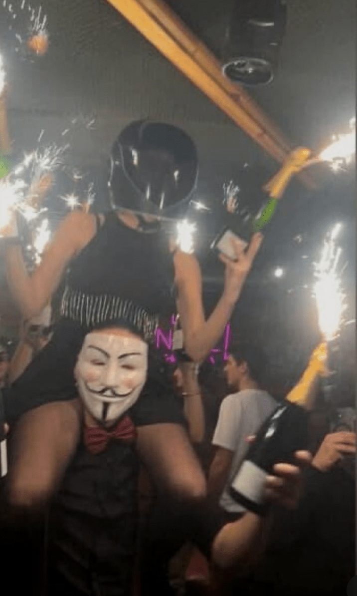 目擊者指當時一名男調酒師將女同事扛在肩上，女方高舉插在瓶口的「噴泉蠟燭」或煙花棒。X@CryptoCronkite