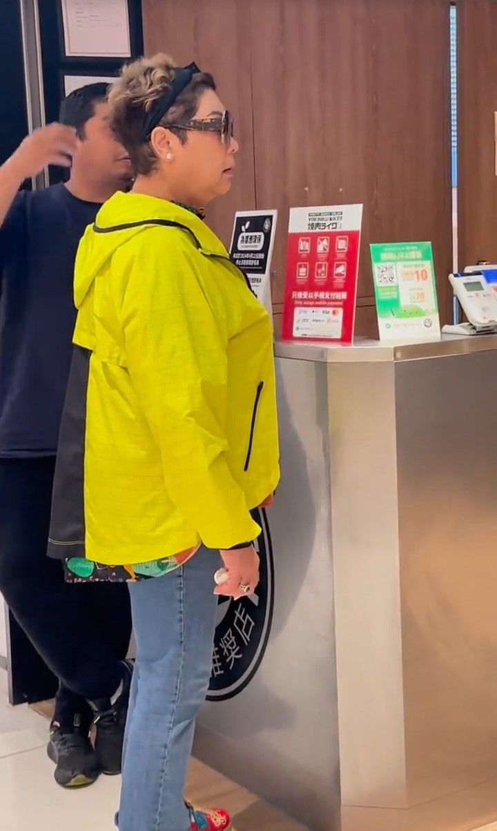 肥媽穿上芥辣黃色外套，與一名疑似是其子的男子在日式燒肉店門外等位。