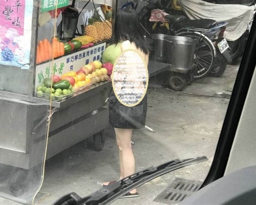 女子手持一杯木瓜牛奶在街上大搖大擺逛街。中時
