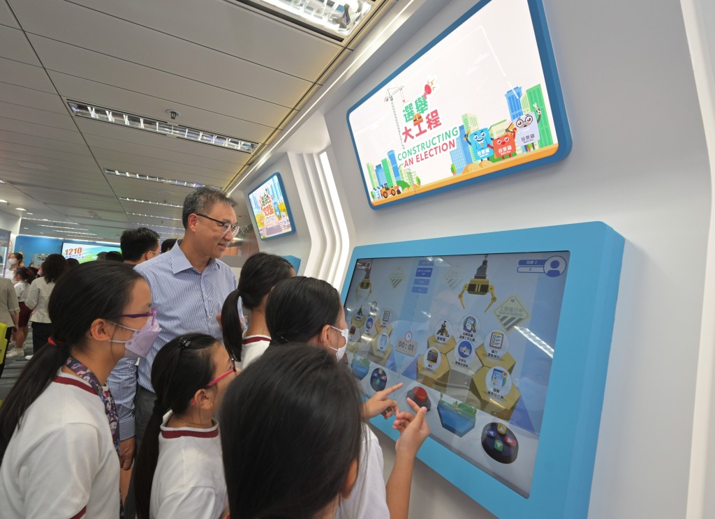 陸啟康和學生試玩中心內全新設計的互動遊戲——「選舉大工程」。政府新聞處圖片