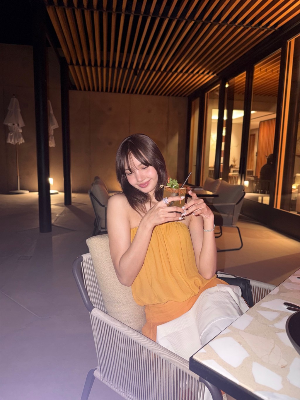 換上黃色晚裝，Lisa手持飲品享受悠閒的夜晚。Lisa