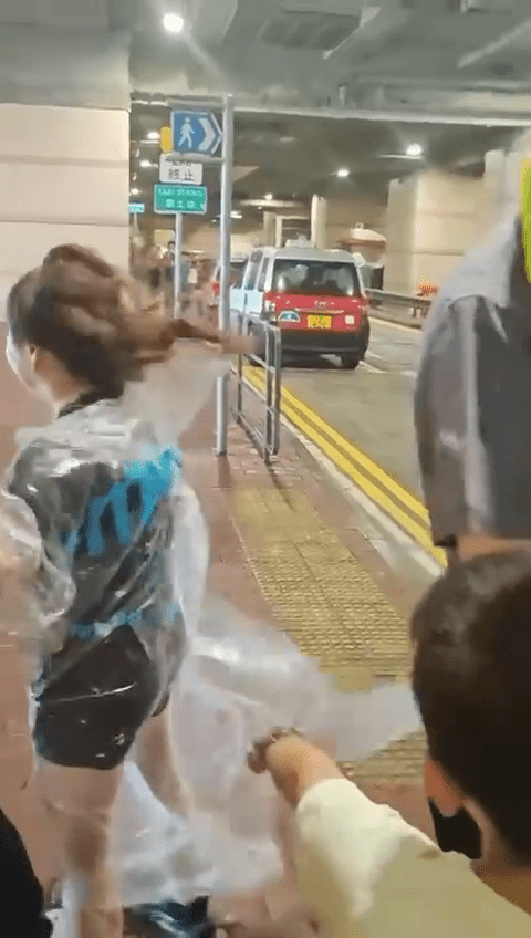 市民躲在巴士站避風,雨衣亦被吹起。 市民躲在巴士站避風,雨衣亦被吹起。