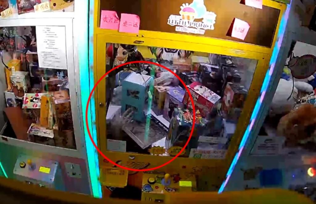 影片清晰看到當灰衣少年似爬入夾公仔機時，一隻手伸進夾公仔機內，並取走一盒玩具。