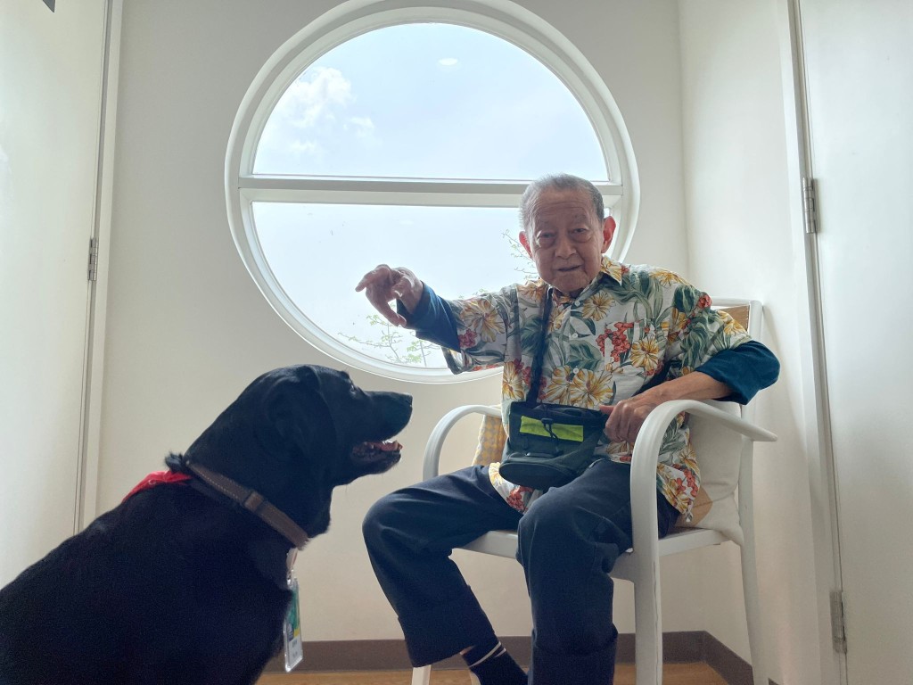 Fruity与83岁院友何鸿昌大玩互动游戏，包括坐下，畀手手。(受访者提供)