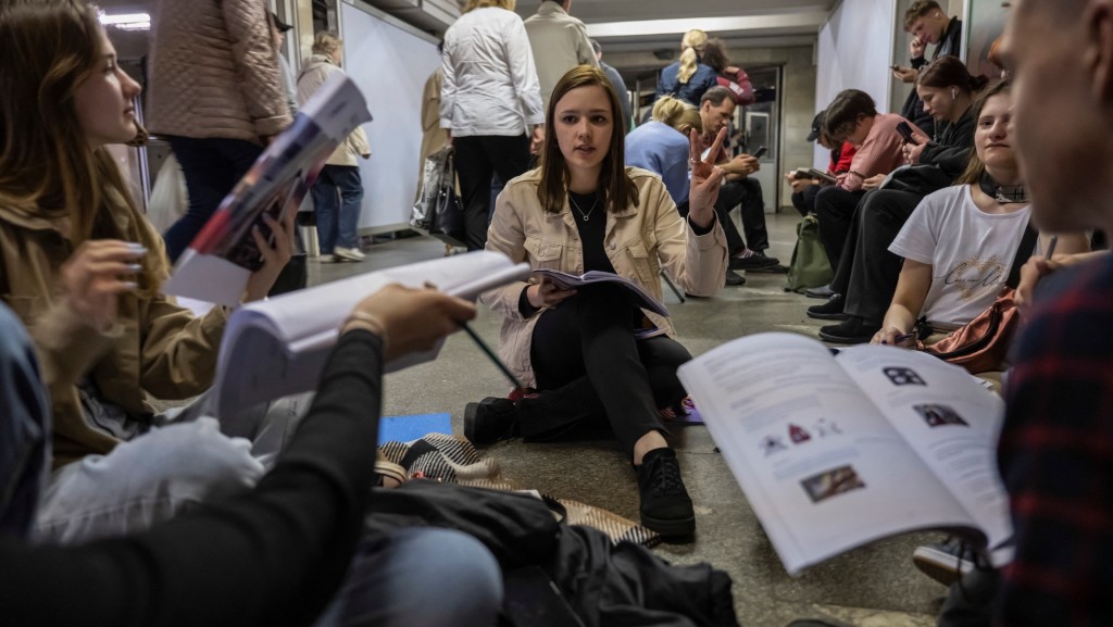 基辅响起空袭警报，民众躲进地铁站避难。一名老师在站内给学生上外语课。 路透社