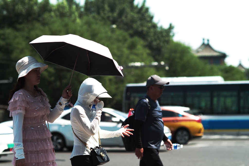 北京市面的行人做足防曬措施。 中新社