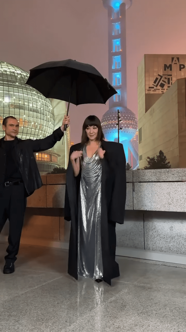 当时上海似乎在落毛毛雨，杨紫琼有工作人员随行撑伞。