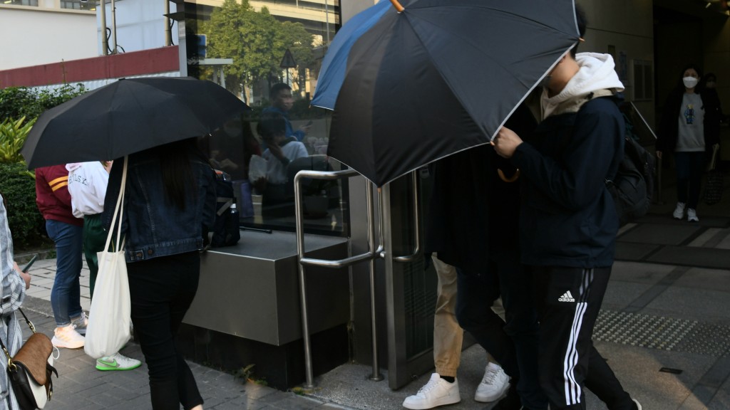 被告范子謙在親友用雨傘掩護下離開。何健勇攝