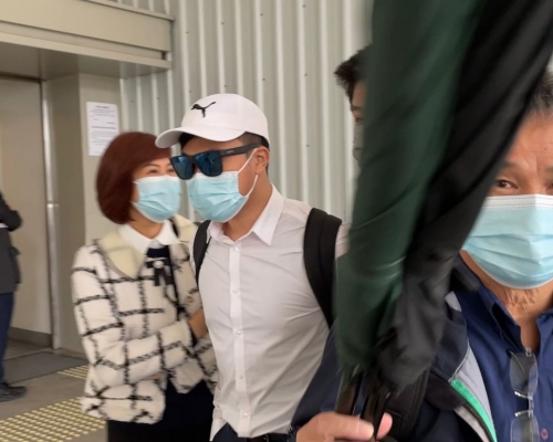 陪同被告王錦鴻(黑超者)的家人舉傘圖阻拍攝。