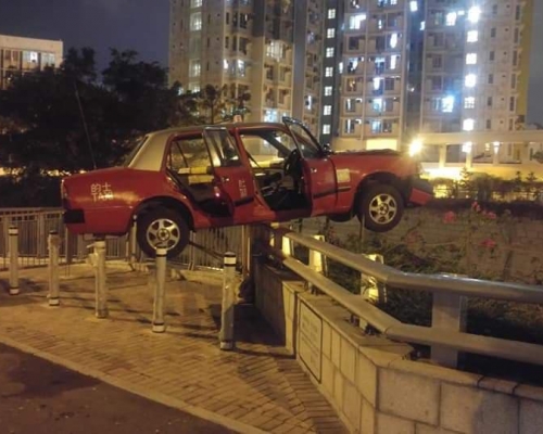 紅的衝上行人路,車身擱在明渠的鐵欄上的照片在網上掀起熱議。「的士司機資訊網 Taxi」fb群組