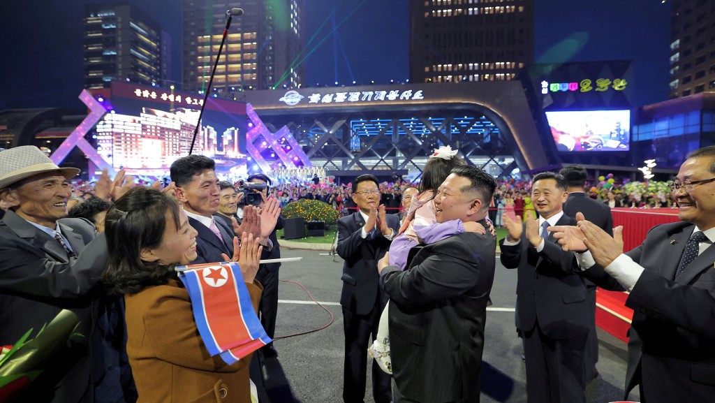 金正恩在平壤和盛新區第三期萬套住宅建設項目落成典禮與小朋友互動。 路透社
