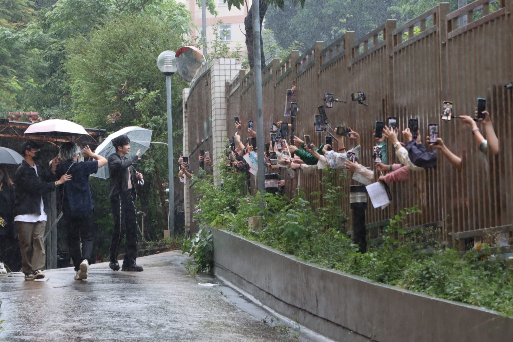 见到粉丝冒雨守候，AL即走近栏杆。