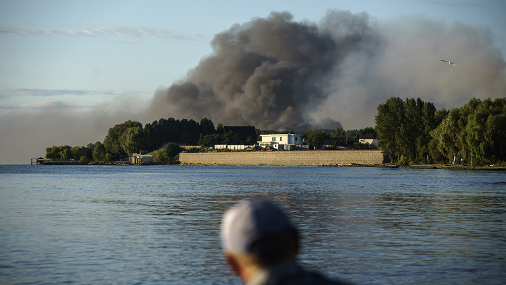 在俄羅斯軍隊對烏克蘭基輔郊區的一個軍事單位發動導彈襲擊後，一名漁民看著濃煙升起。AP