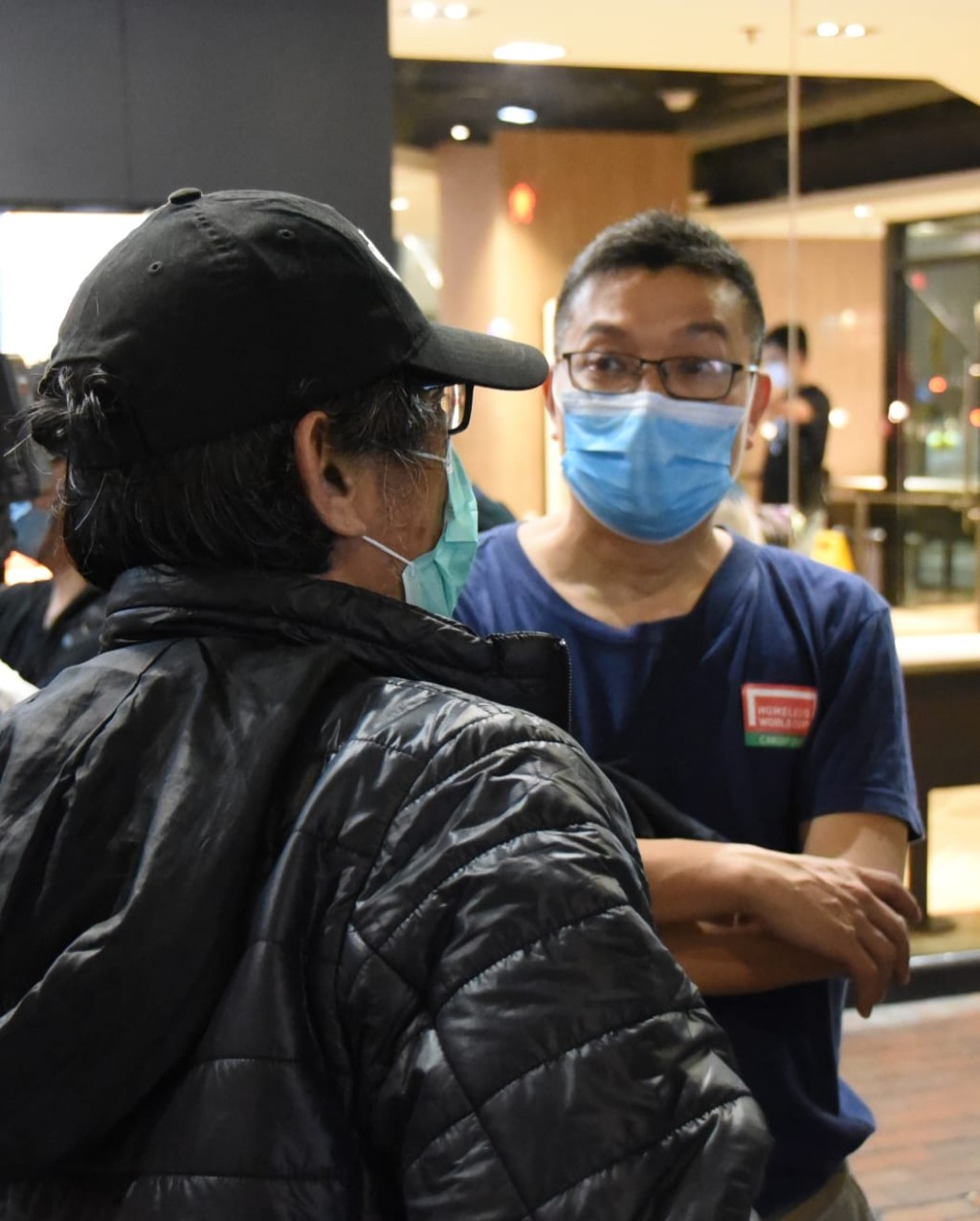 昨夜被逼露宿街頭的「麥難民」張先生(背面),向社區組織協會社區組織幹事吳衛東(正面)訴說情況。 李殷攝