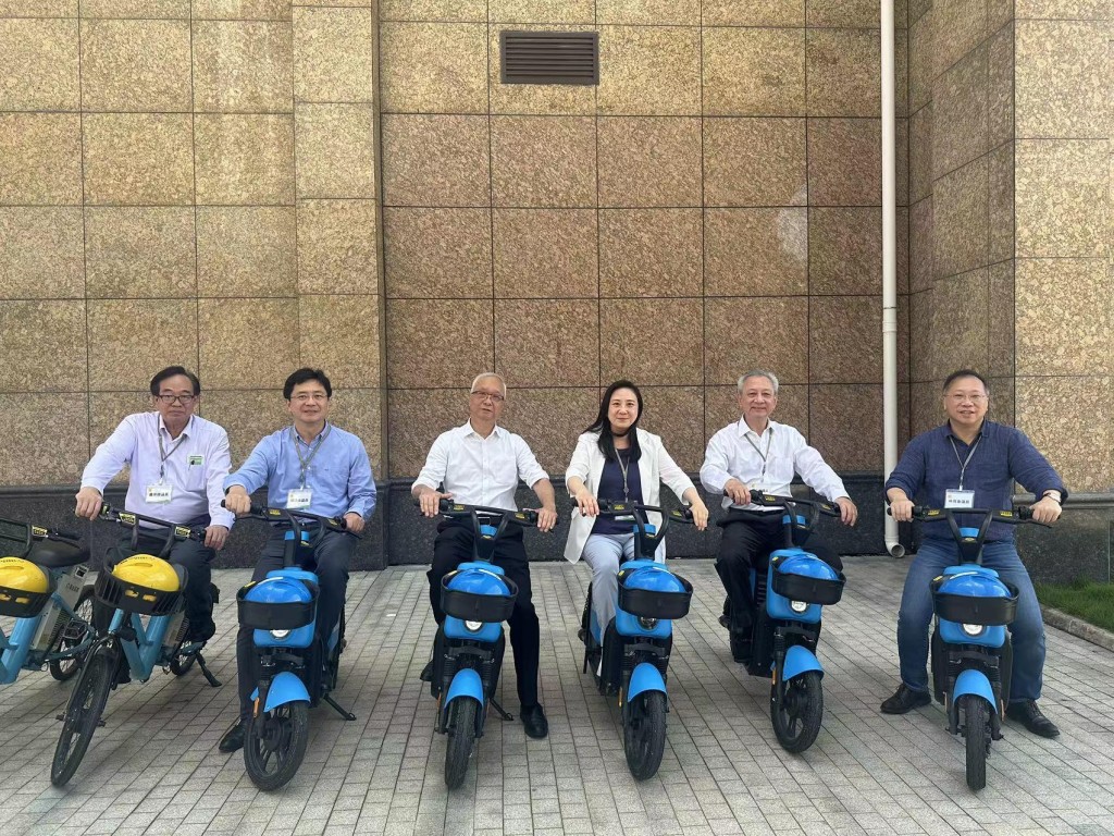 謝展寰（左三）和立法會環境事務委員會訪問團與氫能電單車合照。