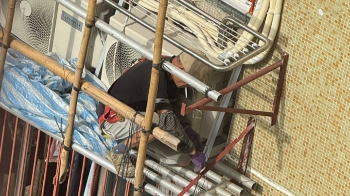 榮園樓有男工人在外牆棚架上工作時，口中叼着燃點的香煙。網圖