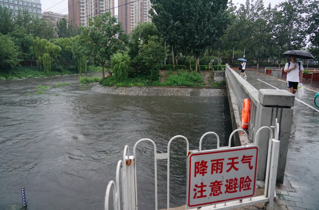 在北京市涼水河周邊，市民冒雨出行。新華社