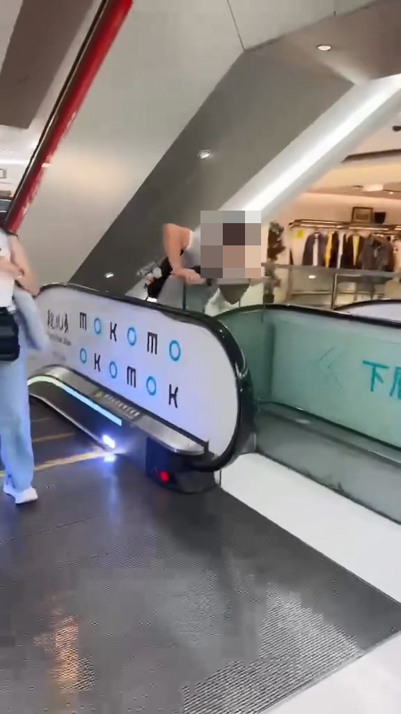 男子翻越玻璃欄杆,爬落扶手電梯中間的銀色蓋板,之後沿著蓋板慢慢爬行到下一層。Threads@showerrrjun片段截圖 男子翻越玻璃欄杆,爬落扶手電梯中間的銀色蓋板,之後沿著蓋板慢慢爬行到下一層。Threads@showerrrjun片段截圖