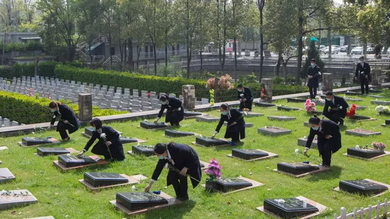 2022年清明期間由工作人員代家屬在墓碑前獻花鞠躬。新華社圖