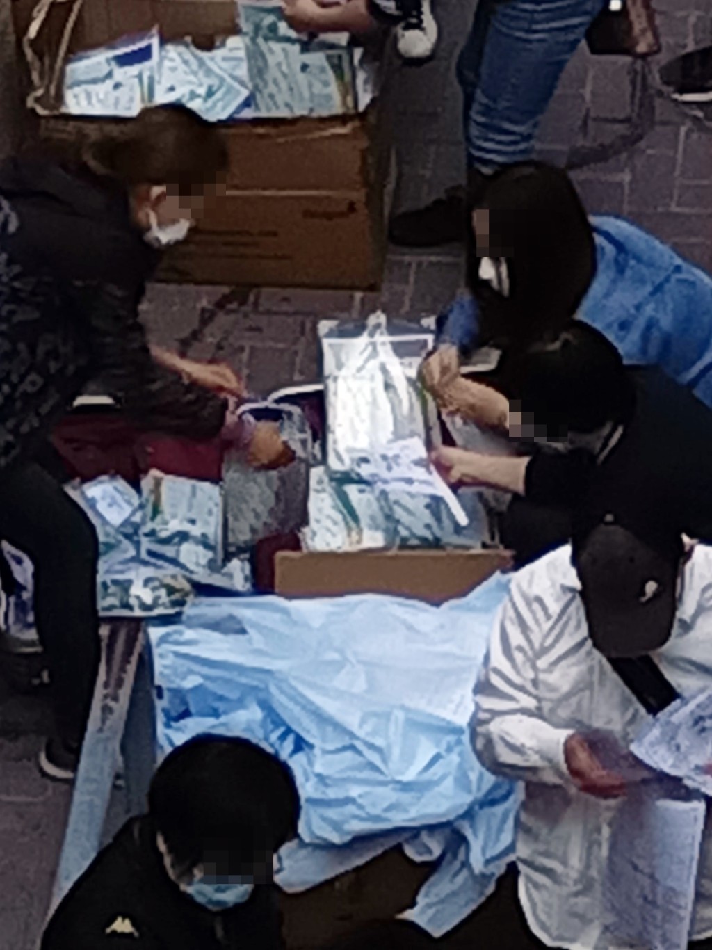 一批人在街頭整理快測包惹來分銷疑雲，但有網民指為政府外判工整理防疫物資包。K Kwong專頁圖片