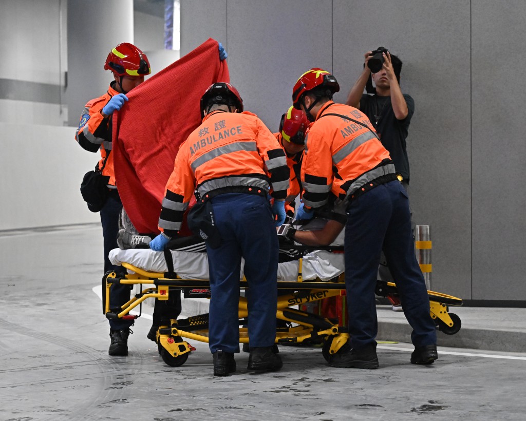 消防處進行電動車火警救援演練期間，救護人員模擬為傷者治理。