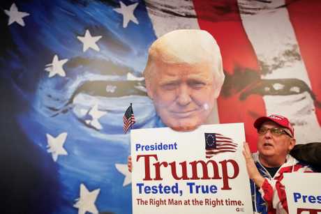 新罕布什尔州一名特朗普支持者举著特朗普肖像和标语牌子。路透社