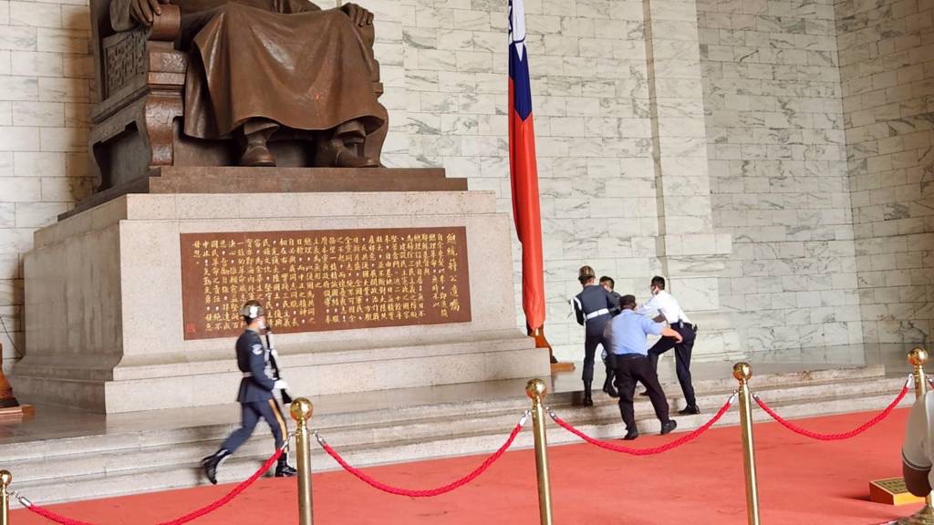 「台灣國」成員持漆彈槍闖中正紀念堂圖掃射銅像，在銅像下與警衛拉扯。 中時