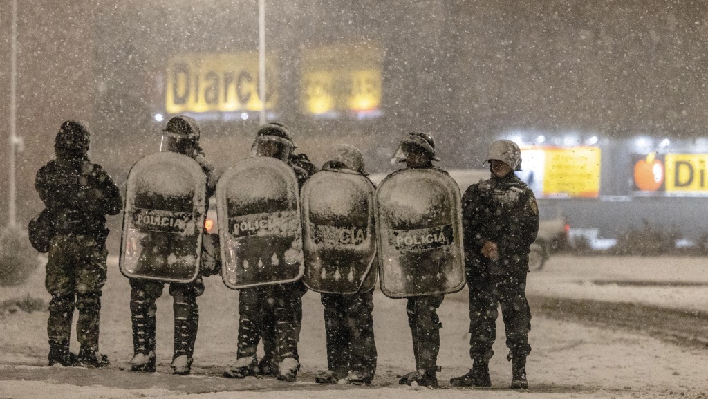 在阿根廷巴塔哥尼亚地区南部小镇巴里洛切，当地居民试图抢劫Diarco超市后，警员冒着雪在超市外戒备。 路透社