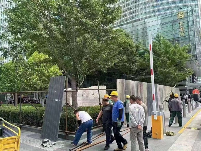 工人围封由光大原董事长唐双宁题字的北京金融街巨石。(网上图片)