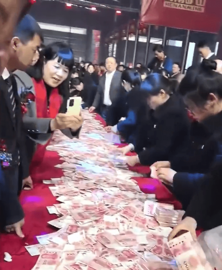 现场50米的长桌红布上铺满人民币现钞，所有一线员工都有机会参与数钱，「数多少拿多少。」