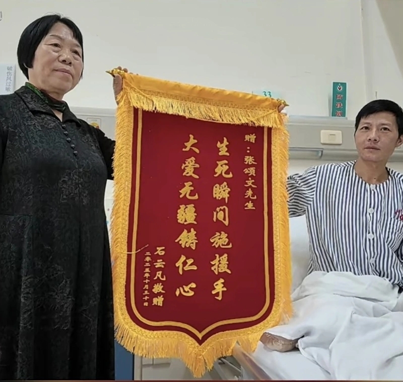 石先生（右）展示著為張頌文準備的錦旗。