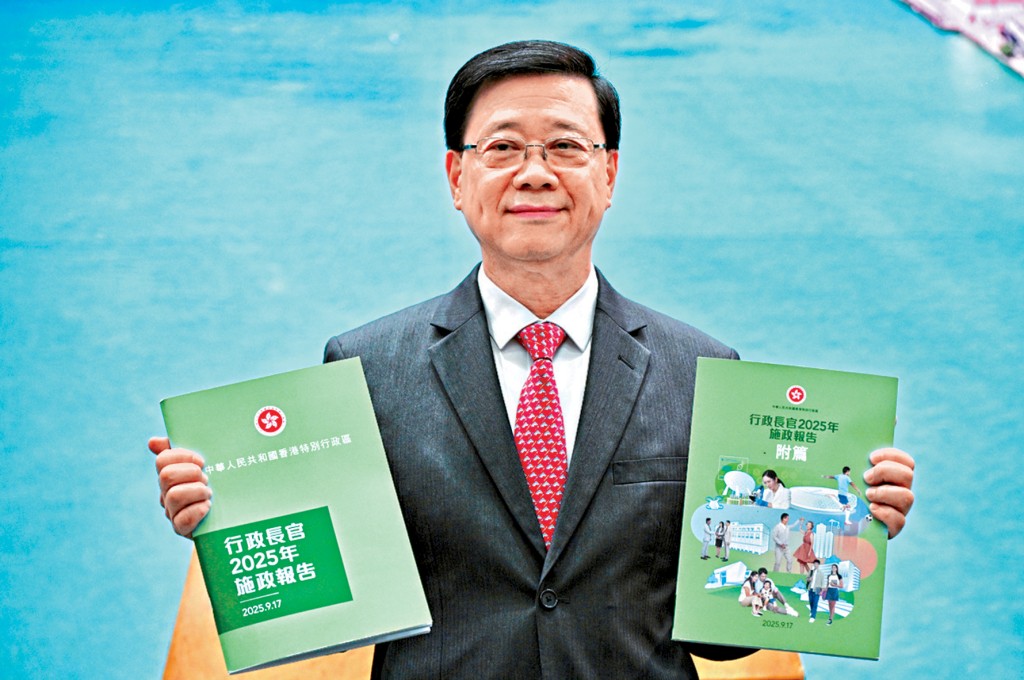 李家超展示今日發表的《行政長官2025年施政報告》及《行政長官2025年施政報告附篇》。