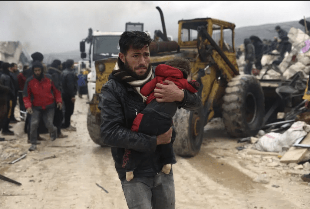 2 月 6 日，星期一，一名男子在敘利亞伊德利卜省土耳其邊境附近的貝斯尼亞村抬著一名地震遇難者的屍體。AP