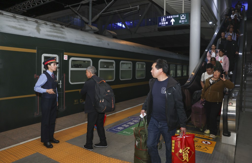 由成都西开往喀什的列车抵达四川广元站，艾尔开牙·多力开（左一）在站台上引导旅客登车。 新华社