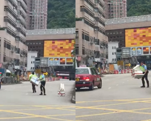 兩名警察正將發泡膠箱搬離馬路中心。網民Kelly Kaa影片截圖