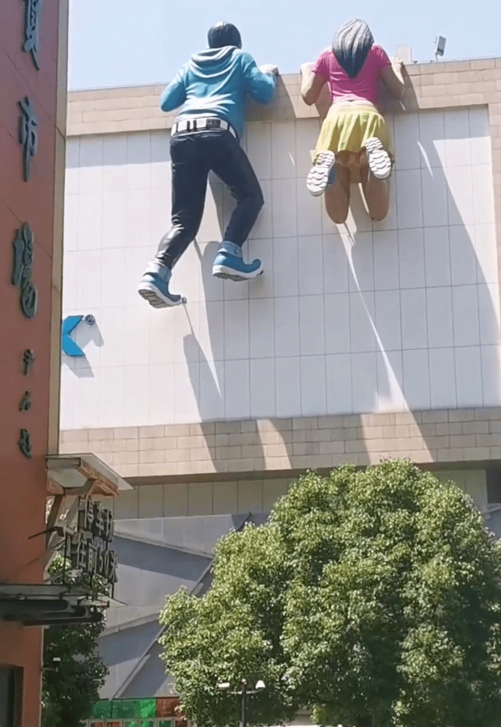 巨大的青年男女以攀爬的姿勢出現商場外牆。