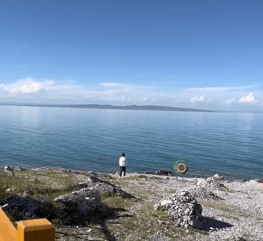 拍摄者称一名男游客翻越护栏，走到青海湖边撒尿。
