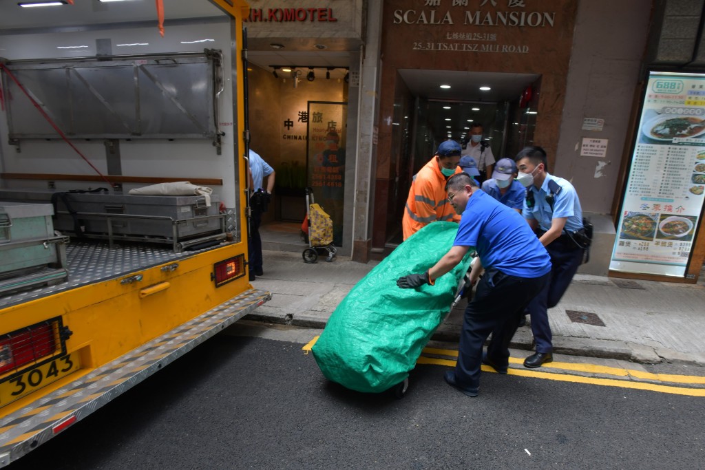 5名仵工與1名警員合力將女死者遺體抬上黑車。 5名仵工與1名警員合力將女死者遺體抬上黑車。