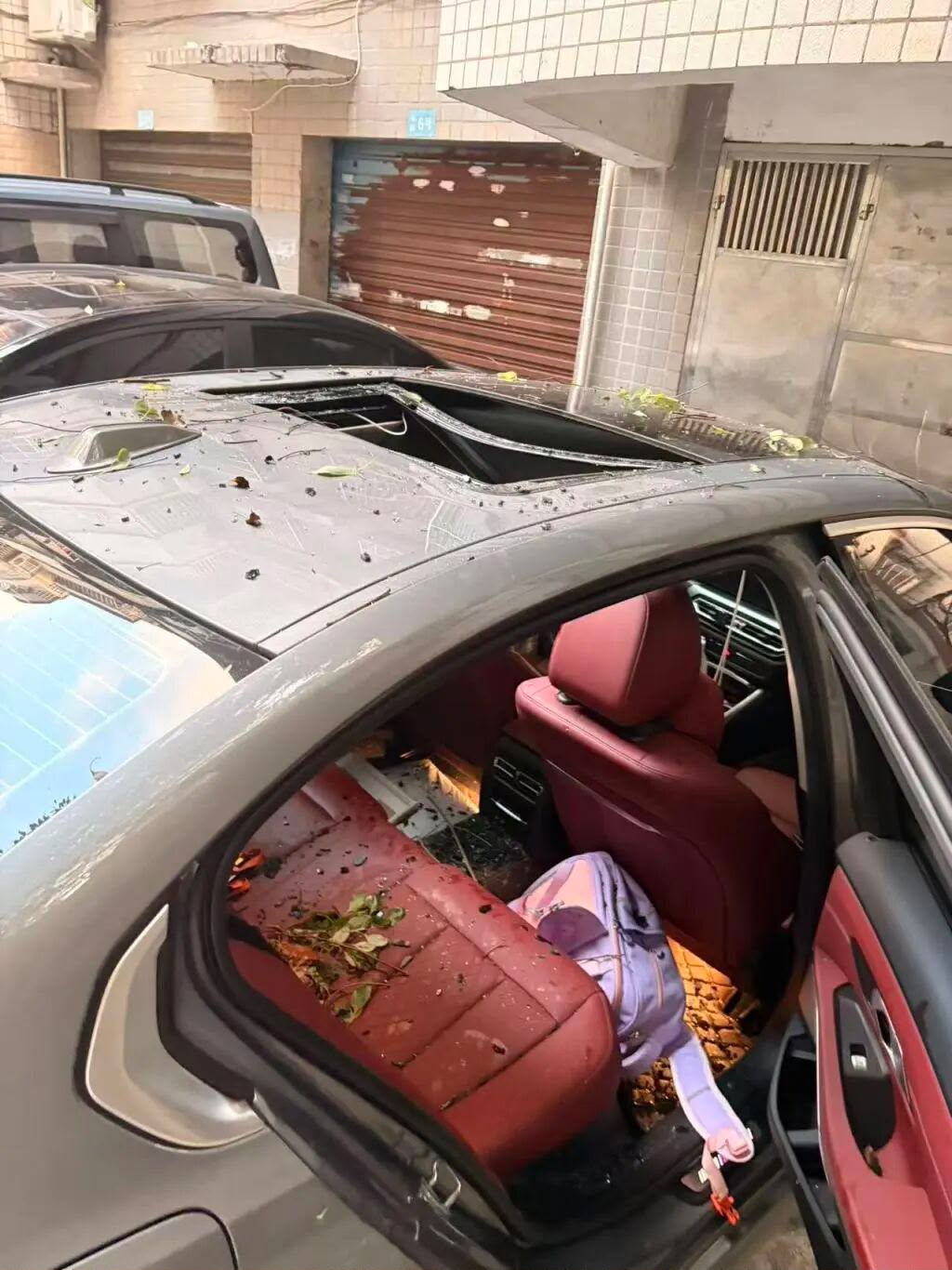 涉事车辆车顶受损，一个书包掉落在后排。澎湃新闻