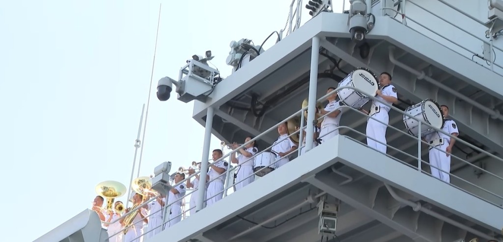 又有軍樂隊於站在艦上高層演奏歌曲。 又有軍樂隊於站在艦上高層演奏歌曲。