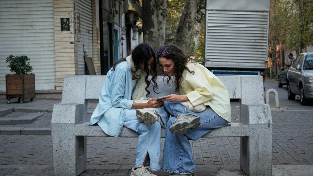 在伊朗德黑兰北部，2名女子在街头使用智能手机。 美联社