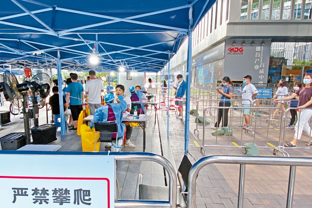深圳疫情升溫，身穿防護服的人員，在南山區軟件園為市民進行核酸檢測。
