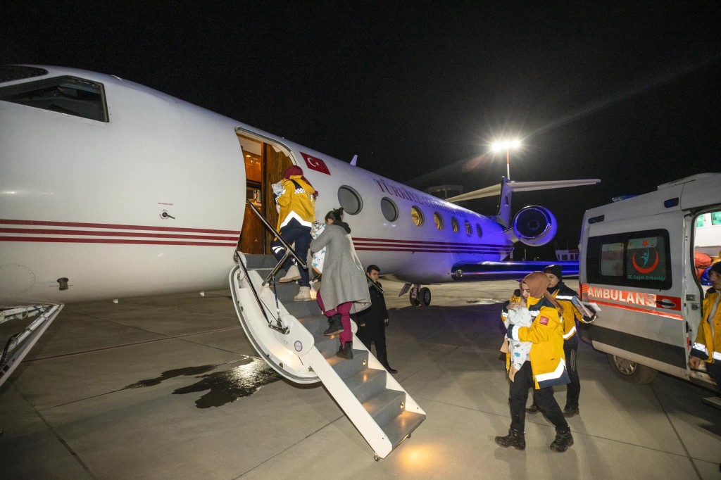 救援人员在寒风中将婴儿包裹在毯子里抱在怀中，小心翼翼地送上机。Emine Erdoğan FB 