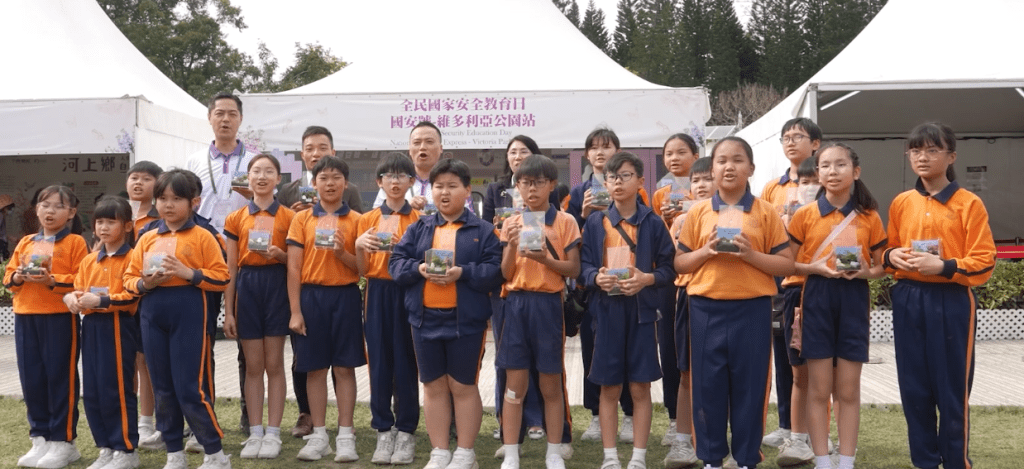 東華三院高可寧紀念小學一班小學生與警隊高層在花卉展國安處攤位內互動製作生態箱。