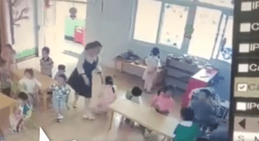 幼稚园老师走近一张枱伸出双手。