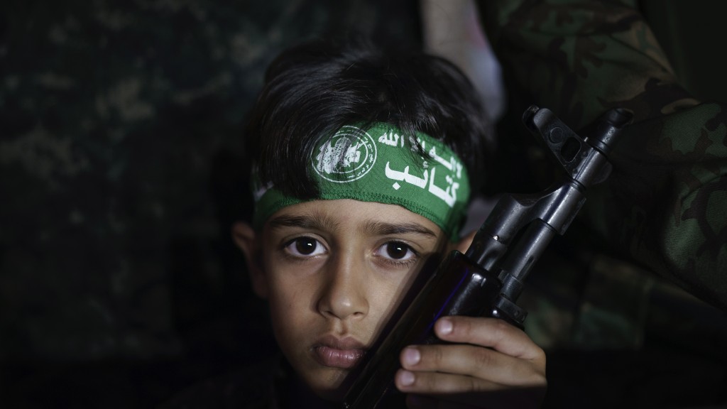 在2021年的以巴衝突，一名男孩手持武器參加哈馬斯的悼念集會。 美聯社