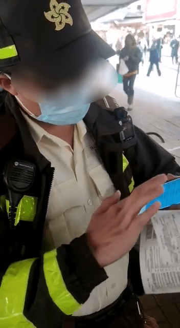 交通督导员拿起手机向该名铁骑士展示抄牌纪录，反驳对方选择性执法指控。网图
